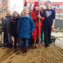 Sandspende für den Schulhof: Kinder auf dem Sandhaufen
